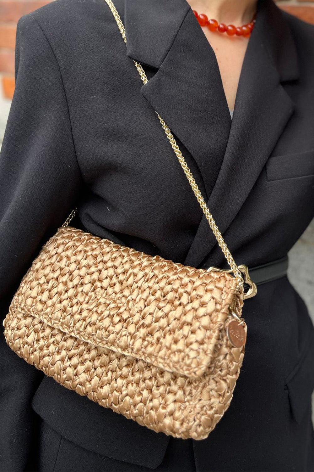 Una mujer usando una cartera tejida color dorado.