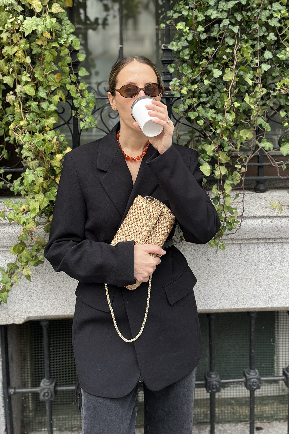 Una mujer usando una cartera tejida color dorado.