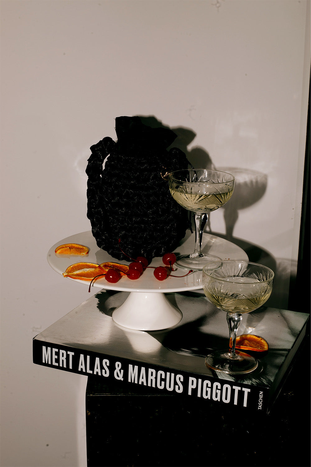 Cartera tejida sobre una pila de libros al lado de un par de cocteles.