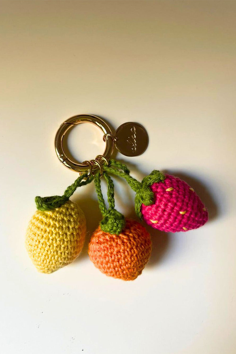 Llavero con tres charms tejidos en forma de frutas.