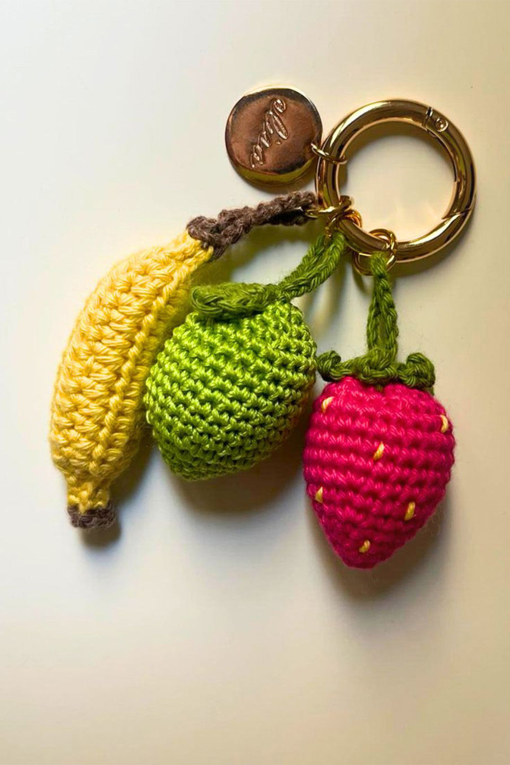 Llavero con tres charms tejidos en forma de frutas.