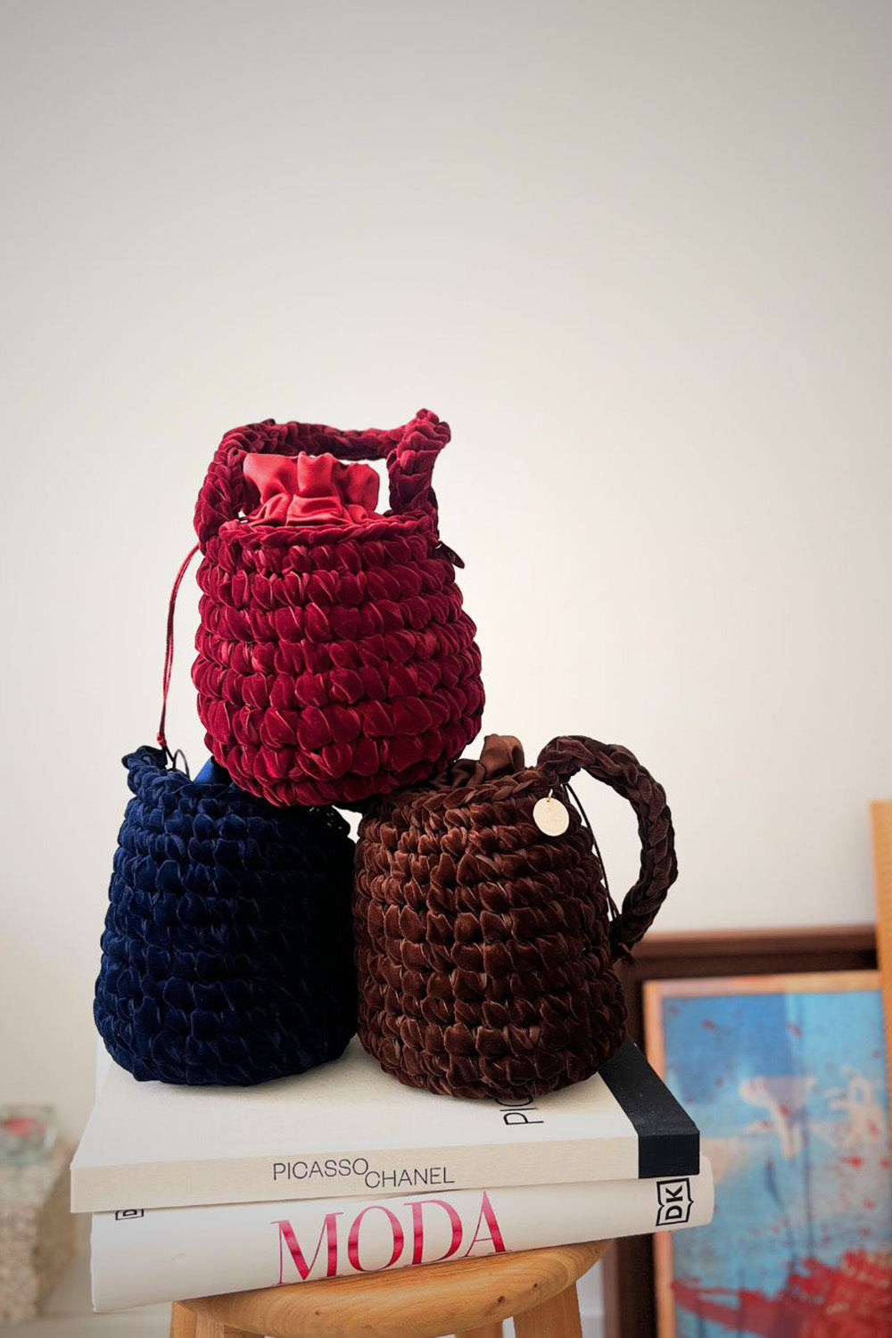 Tres carteras de velvet. Una es color guinda, una es color azul y la otra es de color marrón.