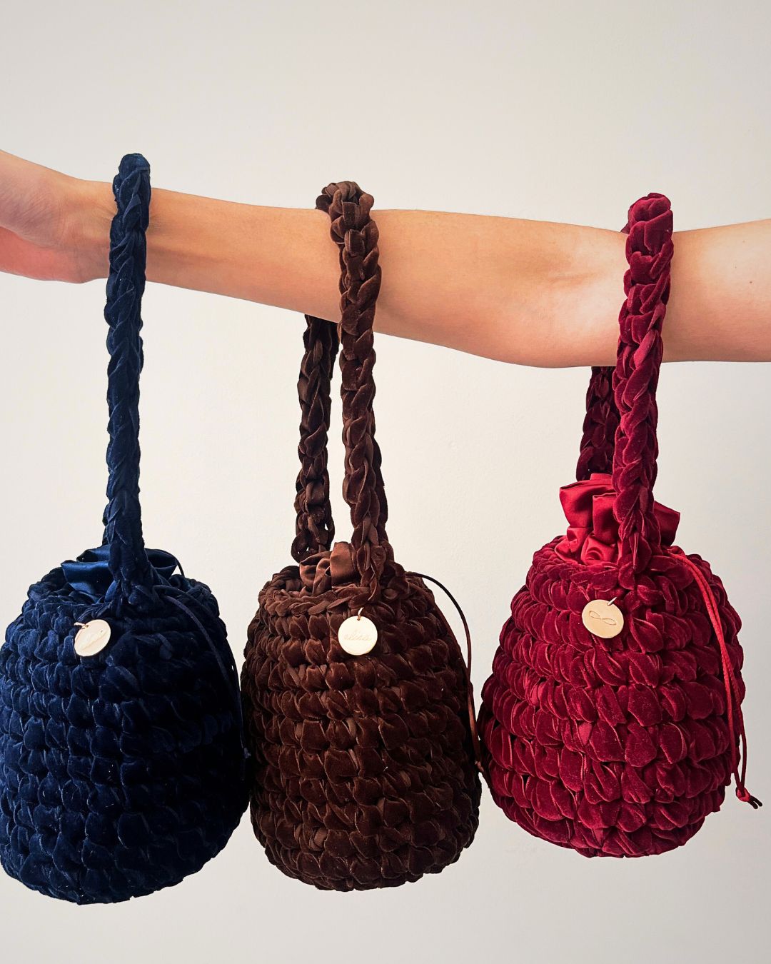 Tres carteras de velvet. Una es color guinda, una es color azul y la otra es de color marrón.