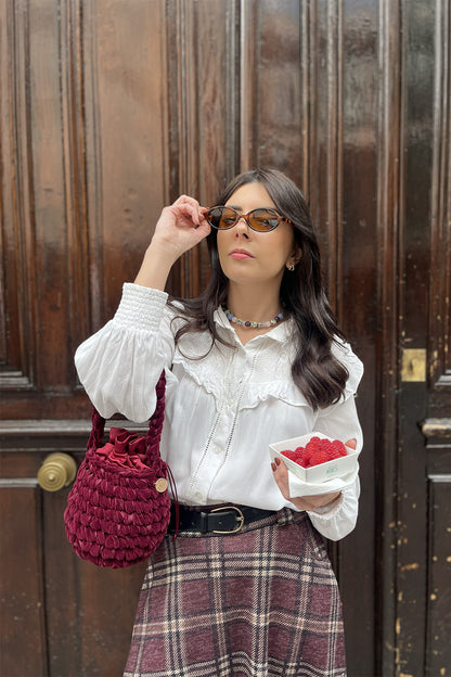 Mujer con una cartera tejida color guinda.