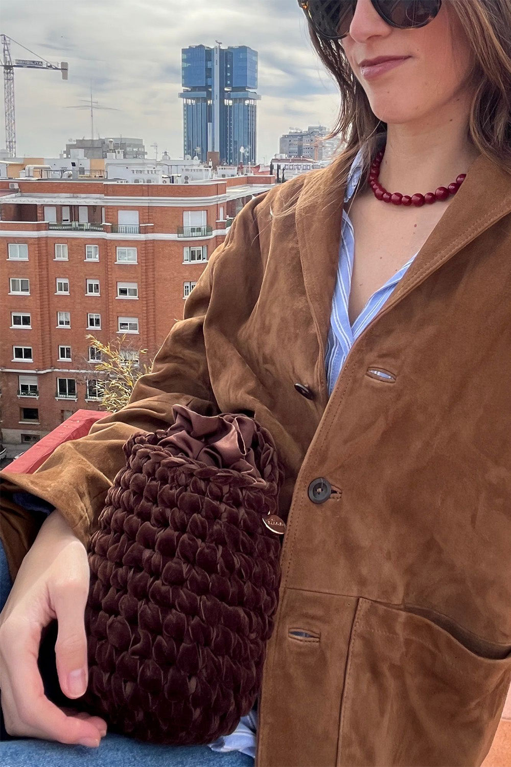 Mujer usando una cartera tejida color marrón.