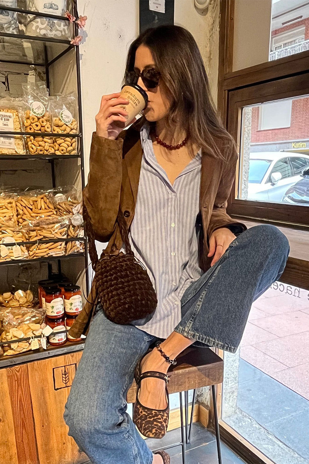 Mujer usando una cartera tejida color marrón.