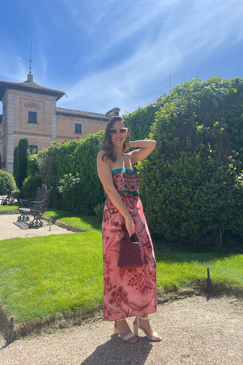 Mujer usando una cartera tejida color guinda metalizado.