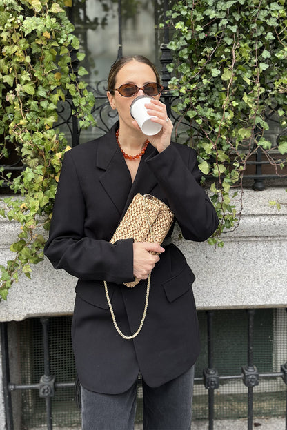 Una mujer usando una cartera tejida color dorado.