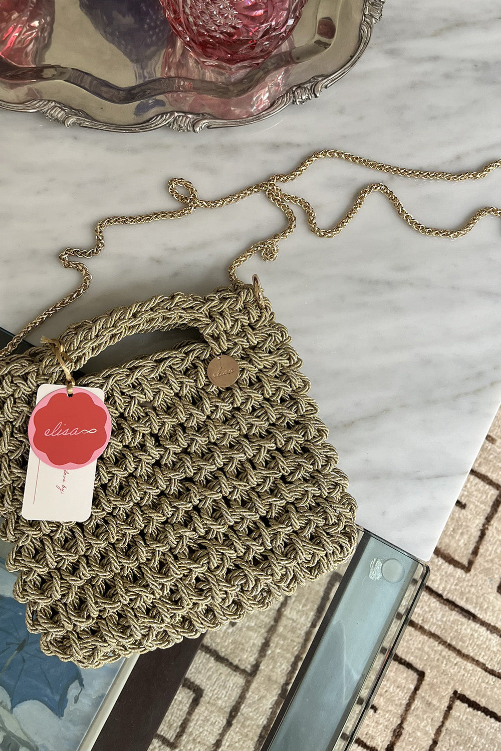 Cartera tejida color beige sobre una mesa.