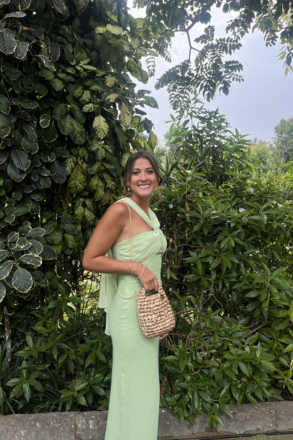 Mujer usando una cartera tejida color dorado.