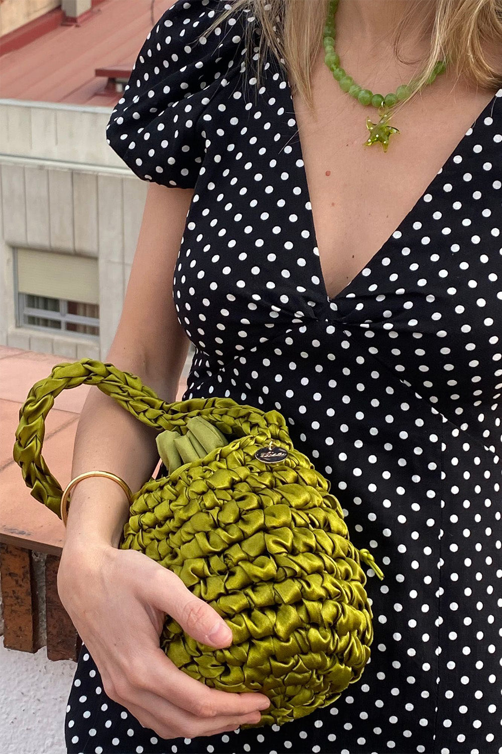 Una mujer sujetando una cartera tejida color pistachio.