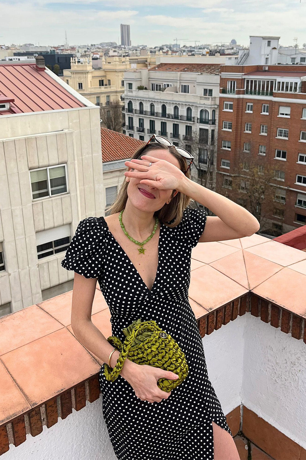 Una mujer sujetando una cartera tejida color pistachio.